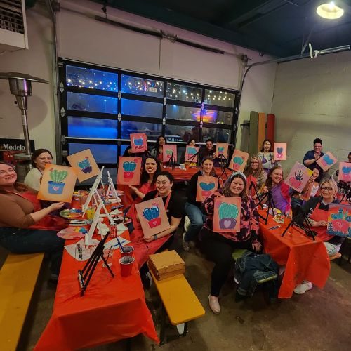 A paint-and-sip class filling the Zócalo garage, everyone holding up their canvas